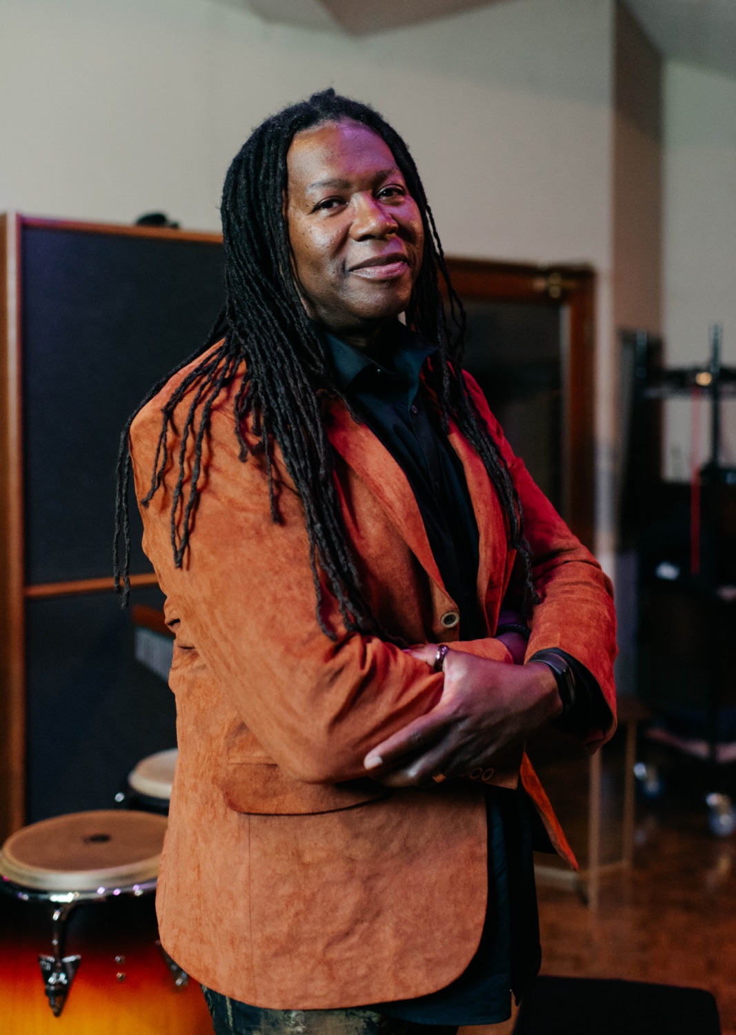 Forrest Robinson standing with arms crossed in the studio, wearing a rust suede jacket